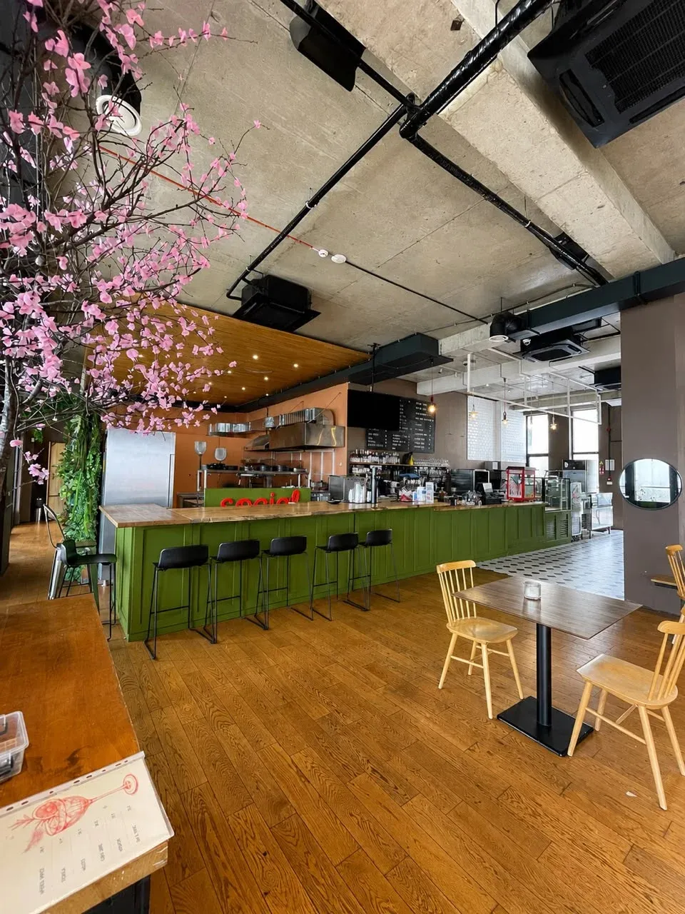 Social Tbilisi bar and café area with green counter, stools, and movable tables