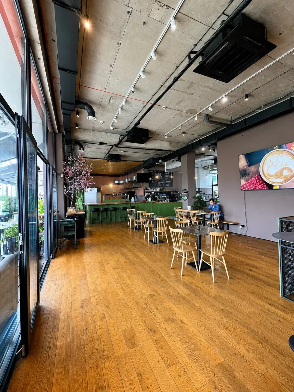 Social Tbilisi main café room with wooden floors, tables, and a green bar