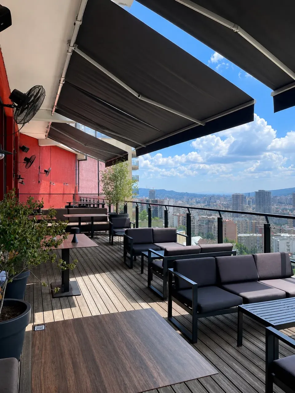 Social Tbilisi veranda seating beneath adjustable awnings with a panoramic Tbilisi view